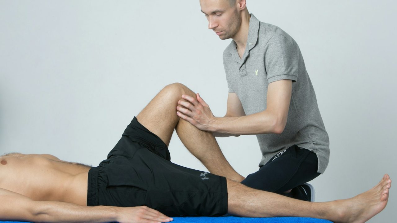 A physical therapist examining a patient's leg during a first appointment at a clinic