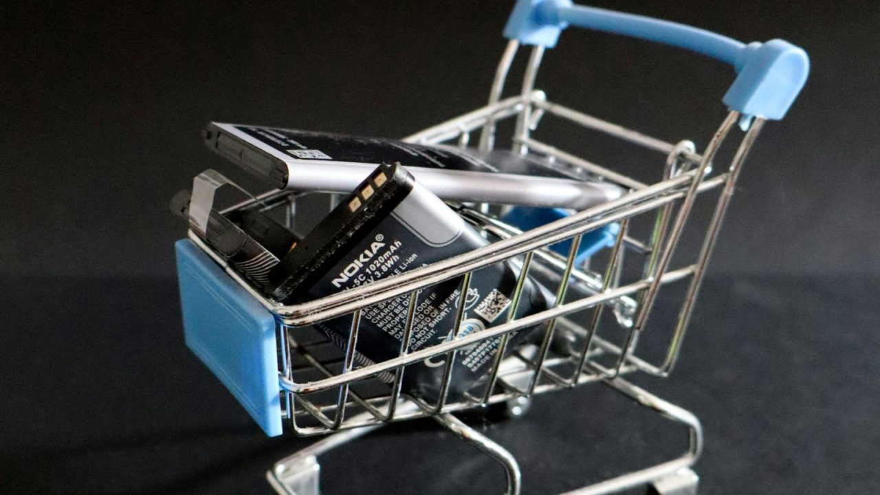 A miniature shopping cart holding a smartphone, representing an online store recovering abandoned carts through mobile messaging